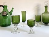 Des bouteilles et des verres sont alignés sur une table, à côté d'un pichet