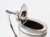 a silver watering can with a spoon in it