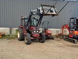 the tractor is parked in front of a building with a crane attached to it