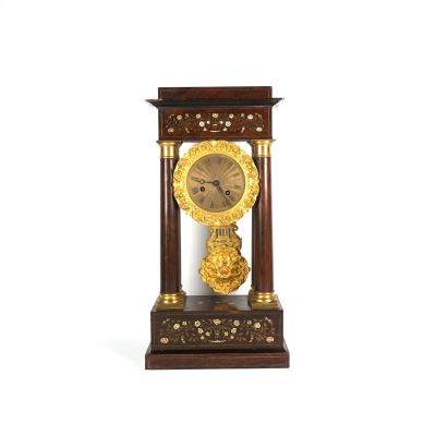 une horloge posée sur un support sur une surface blanche