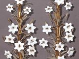 pair of white flowers on gold metal candlesticks against a gray background