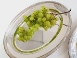 a plate with a bunch of grapes on it next to a plate with a bunch of grapes on it