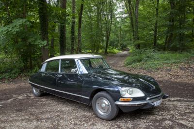 a black and white car parked on a dirt road in the woods