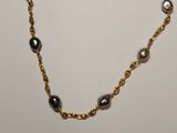 a close up of a gold chain bracelet with pearls on it