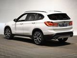 the rear end of a white bmw suv parked on a checkered floor