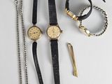 trois montres et une paire de ciseaux sont posés sur une table