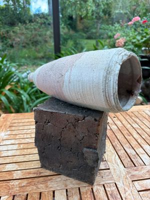 un vase en ciment posé sur une table en bois