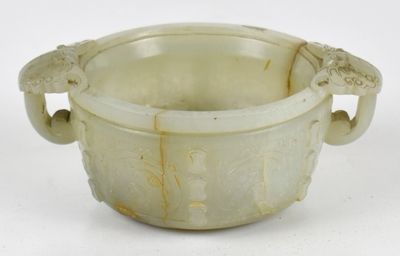 un bol blanc muni d'anses, posé sur une surface blanche