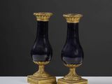 une paire de vases noirs et dorés posés sur une table blanche