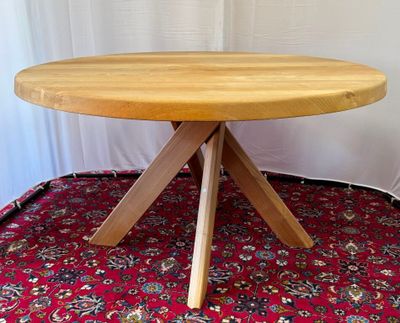 une table en bois à trois pieds, posée sur un tapis rouge