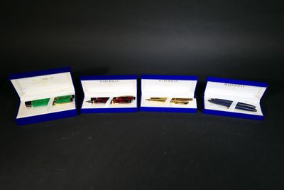 four different pens are lined up in a row on a black surface