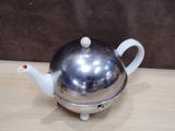 a silver teapot on a wooden table with a brown background