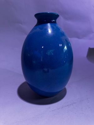 un vase bleu posé sur une table à côté d'un autre vase bleu
