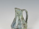 an old green pitcher sitting on top of a white table