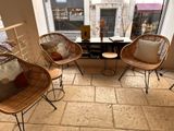 three wicker chairs sit in front of a window in a coffee shop