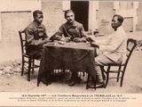 trois hommes assis à une table devant un immeuble