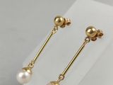 a pair of pearl and gold earrings on a white stand