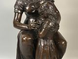 bronze statue of a woman holding a child on a wooden base
