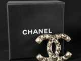 a chanel broocher in the shape of a chanel logo