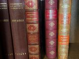 several old books are lined up on a shelf in a library