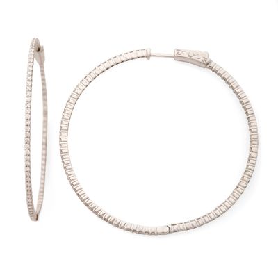 un gros plan sur une paire de boucles d'oreilles créoles sur fond blanc