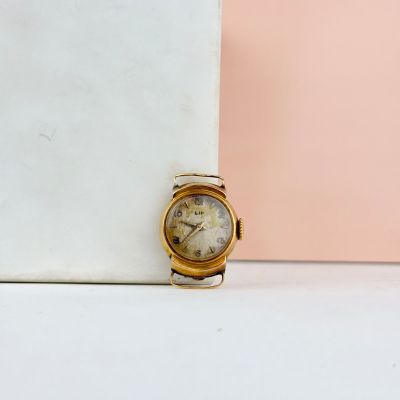 une image représentant une montre en or posée sur un bloc de marbre