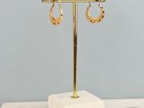 a pair of gold hoop earrings on a marble stand