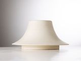 un vase blanc posé sur une table à fond blanc