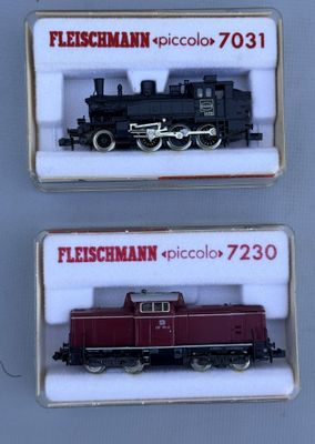 two miniature trains are displayed in a display case on a white surface