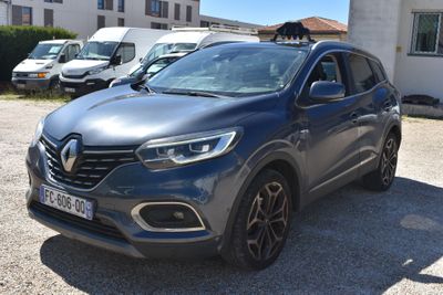 La voiture grise est garée devant un bâtiment blanc.