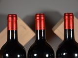 three bottles of wine sitting on a wooden shelf