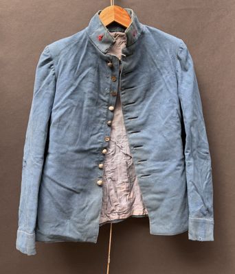 une vieille veste bleue suspendue à un cintre accroché au mur