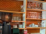 une cuisine avec des placards orange et une cafetière posée sur le plan de travail