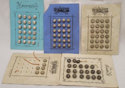 several old buttons are sitting on a piece of paper on a table