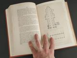 a hand that is holding an open book on a table