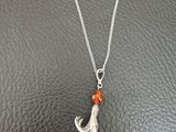 un collier en argent orné d'un pendentif en forme de chat, posé sur une surface noire