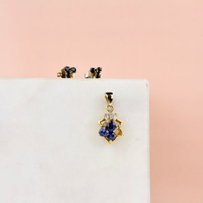boucles d'oreilles plaquées or ornées de pierres bleues et blanches sur fond rose