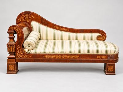 une chaise longue ancienne en bois avec des coussins rembourrés à rayures