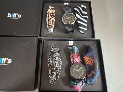 trois boîtes contenant des montres et des cravates, posées sur une table