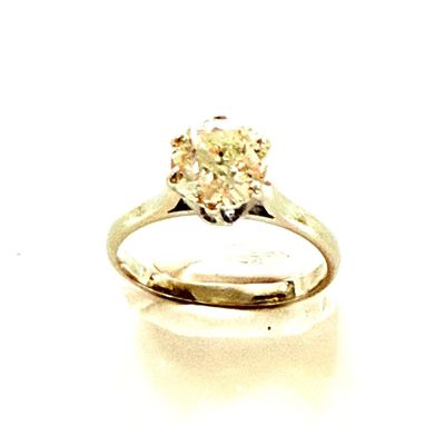 une photo d'une bague sertie d'un diamant jaune posée sur une surface blanche