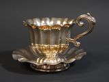 une tasse et une soucoupe anciennes en argent sur fond noir