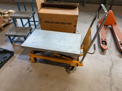 un chariot à roulettes sur lequel est posée une caisse, dans un entrepôt