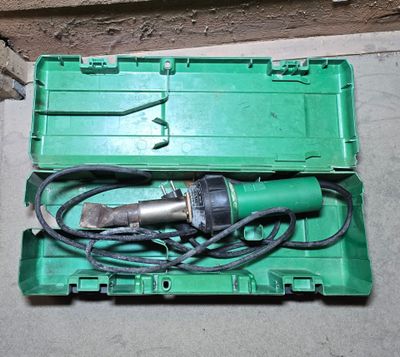 a green box with a drill in it sitting on the floor