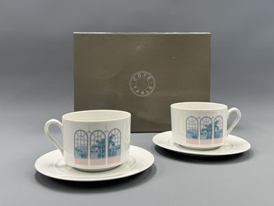 deux tasses à café et leurs soucoupes, ainsi qu'une boîte, posées sur une table