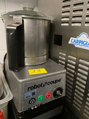 un robot assis dans une cuisine, à côté d'une poubelle