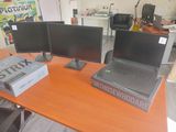 three monitors and a laptop on a desk in a room