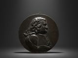 a bronze medallion of a man holding a book