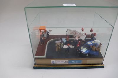 une vitrine dans laquelle sont exposées des figurines représentant des personnes et une voiture