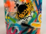 une tasse colorée ornée de graffitis, posée sur une table