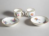 three cups and a saucer are sitting on a table